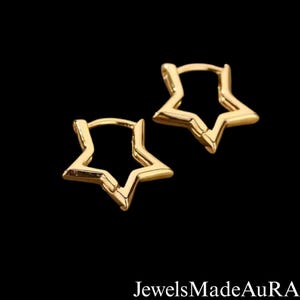 May include: A pair of gold-colored star-shaped hoop earrings. The earrings are made of a shiny metal and are set against a black background. The text "JewelsMadeAuRA" is at the bottom of the image.