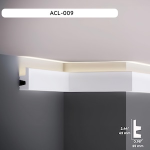 Può includere: Modanatura bianca installata in un angolo, con il testo "ACL-009" in alto. La modanatura è alta 62 mm e larga 25 mm. La modanatura è installata su un soffitto bianco e una parete grigia.