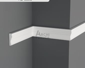 Könnte beinhalten: Weiße Zierleiste in einer Ecke installiert, mit dem Text "AB-6050" und dem Logo "Archi Tualca". Die Leiste ist ein dekoratives Element, wahrscheinlich für Innenarchitektur oder Architektur. Die Ecke ist dunkelgrau gestrichen.