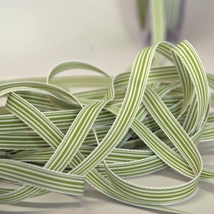 May include: A close-up shot of a collection of green and white striped ribbon. The ribbon is tightly woven with a subtle sheen. The stripes are evenly spaced along the length. This ribbon is suitable for crafts or gift wrapping, and is likely sold by the metre.