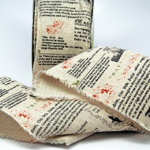 May include: A close-up of a beige fabric ribbon with black text printed on it. The text includes the words "On 9th July" and "Canada was a little sand to be leg". The ribbon has a frayed edge and is decorated with small red and green floral designs.