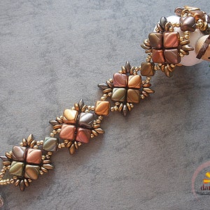 May include: A beaded bracelet with a geometric pattern in shades of brown, gold, and green. The bracelet is made with small seed beads and features a clasp closure.