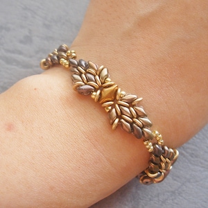 May include: A gold and brown beaded bracelet with a geometric design. The bracelet is made with small, round beads and features a central star-shaped bead.