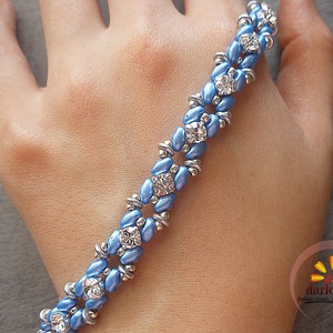 May include: A light blue beaded bracelet with silver-tone details and clear, square-cut rhinestones. The bracelet showcases a repeating pattern of blue beads and sparkling crystals, creating a delicate and elegant design.