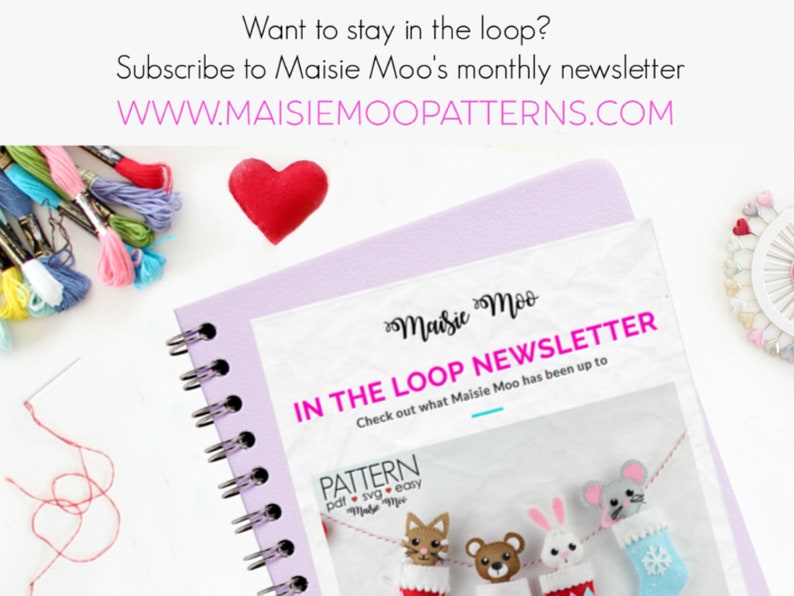 May include: A white envelope with the text "Maisie Moo IN THE LOOP NEWSLETTER Check out what Maisie Moo has been up to" and a graphic of four felt stockings with animal faces. The envelope is on a purple notebook with a spiral binding.
