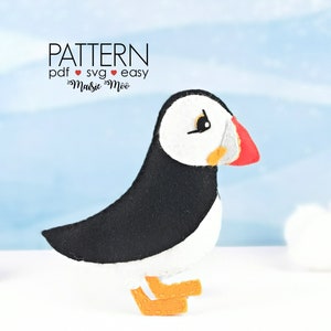 Può includere: Un modello in feltro per un simpatico puffin bianco e nero con becco e piedi arancioni. Il modello è disponibile in formato PDF e SVG ed è etichettato come "facile".