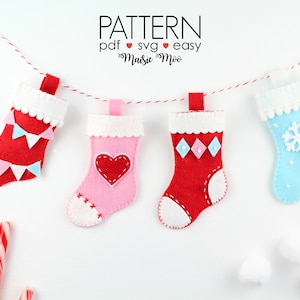 Könnte beinhalten: Eine Girlande aus vier Filz-Weihnachtsstrümpfen mit verschiedenen Designs. Die Strümpfe sind rot, rosa, blau und weiß. Die Designs beinhalten Flaggen, ein Herz, Diamanten und eine Schneeflocke. Der Text "PATTERN pdf svg easy" befindet sich oben im Bild.