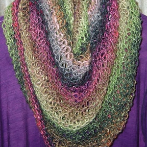 May include: A multi-coloured, open-weave cowl scarf, featuring shades of green, purple, pink, and brown. The scarf is displayed over a purple garment, highlighting its textured, knitted construction. This accessory is ideal for adding warmth and style to any outfit.