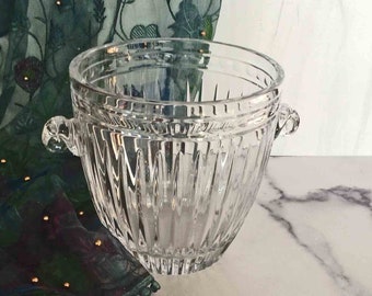 Könnte beinhalten: Ein klarer Glaseiseimer mit zwei Griffen. Der Eimer hat ein strukturiertes, geripptes Design.