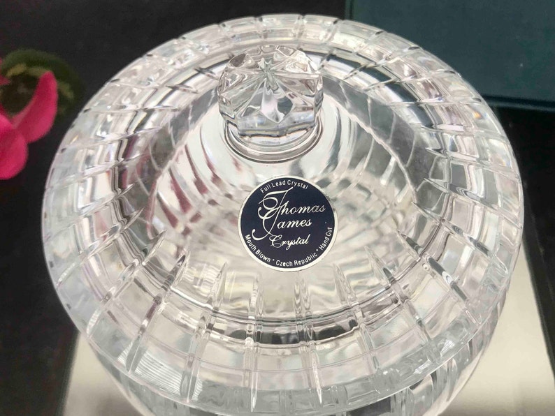 Puede incluir: Tarro de cristal transparente con tapa, con un patr&oacute;n tallado en diamante. La tapa tiene un pomo facetado. Una etiqueta en el tarro dice "Thomas James Crystal, Mouth Blown, Czech Republic, Hand Cut."