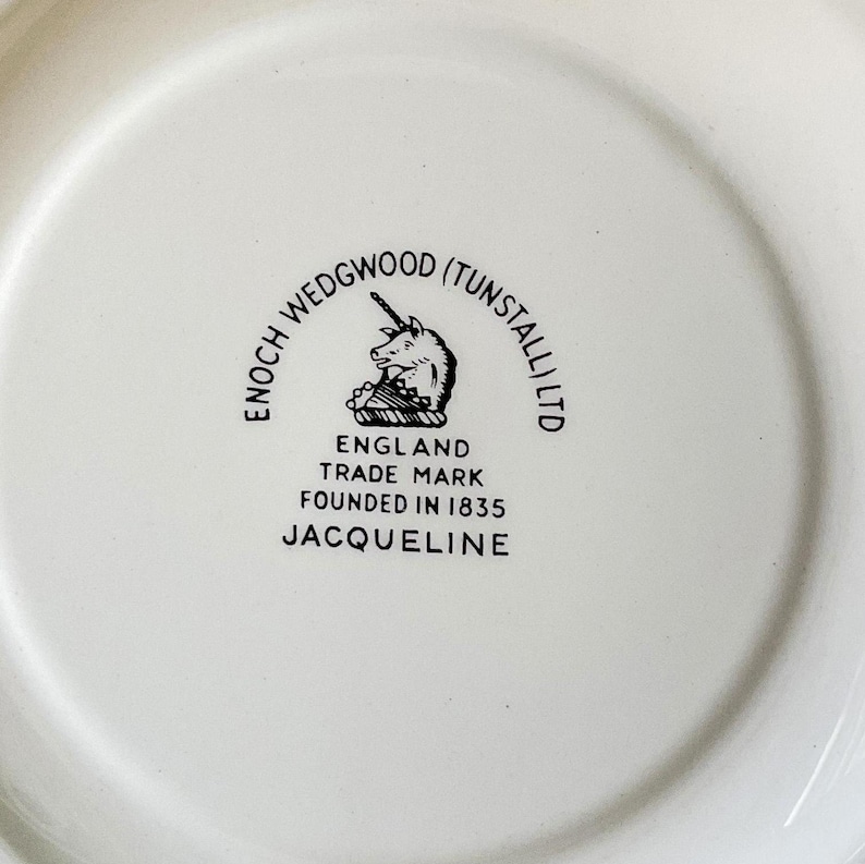 May include: A white ceramic plate with a black and white logo that reads "Enoch Wedgwood (Tunstall) Ltd. England Trade Mark Founded in 1835 Jacqueline"