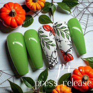 May include: Green and white nail art with a Halloween theme. The nails feature a glossy green color and white nails with pumpkin and spiderweb designs. The image includes pumpkins, leaves, and the text "press release NAIL ART".