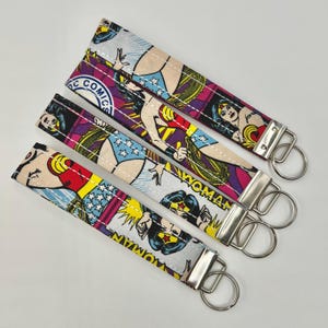 Puede incluir: Cuatro llaveros de tela con un diseño de cómic de Wonder Woman. Los llaveros tienen un anillo de metal plateado y están impresos con imágenes de Wonder Woman con su traje clásico, junto con las palabras "DC Comics" y "Wonder Woman."