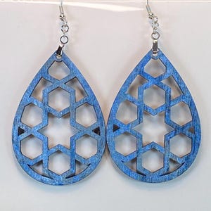 May include: A pair of blue teardrop-shaped earrings with a geometric pattern. The earrings are made of wood and have silver hooks.