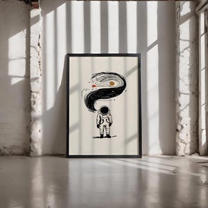 Puede incluir: Lámina artística enmarcada en negro con una ilustración minimalista de un astronauta. El astronauta está representado con un traje espacial, con un remolino negro que emana del casco, que contiene un sol y otros elementos celestes. El fondo es blanquecino.
