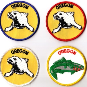 May include: Four embroidered patches featuring the word "OREGON". Three patches have a yellow background with a white seal illustration, and the fourth has a green fish. Each patch has a different colored border: blue, red, white, and yellow.