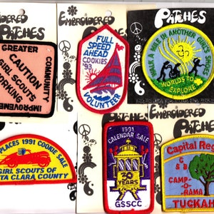 May include: A collection of nine embroidered patches featuring various Girl Scout themes. The patches are colorful and feature different designs, including a car, a sailboat, a sun, and a tree. The patches are all rectangular or oval shaped and have a black outline. The text on the patches includes "Girl Scouts", "Caution", "Community", "Volunteer", "Going Places", "1991 Cookie Sale", "Santa Clara County", "Walk a Mile", "Worlds to Explore", "1991 Calendar Sale", "30 Years", "GSSCC", "Capital Region", "Camp-O-Rama", "Tuckahoe", and "1985".