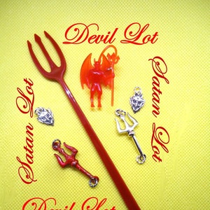 May include: A collection of devil-themed items on a yellow background. The items include a red plastic trident, a small red devil figurine, silver devil head charms, and a silver trident charm. The words "Devil Lot" and "Satan Lot" are written in red script.