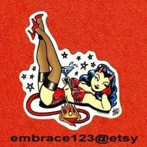 May include: A sticker featuring a cartoon devil woman in a red outfit, holding a martini. Her legs are raised, and she has a tail and horns. The sticker is outlined in white, with a red background and the text "embrace123@etsy".