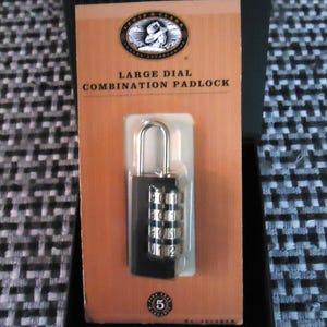 May include: A black combination padlock with silver dials and a silver shackle is displayed in its original packaging. The packaging is orange and features the text "LARGE DIAL COMBINATION PADLOCK". The padlock has the number "5" on the bottom.