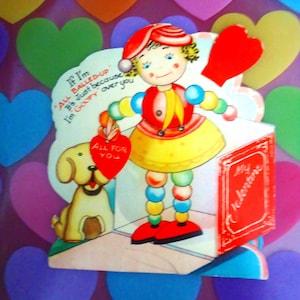 May include: A vintage Valentine's Day card featuring a cartoon doll with a red hat and a yellow dress. The doll holds a red heart that says "ALL FOR YOU". A cartoon dog sits beside the doll. The card has text that reads "If I'm ALL BALLED-UP It's just because I'm GOOPY over you".
