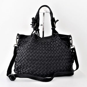 Pu&ograve; includere: Borsa a mano in pelle nera intrecciata con manico superiore e una lunga tracolla regolabile.