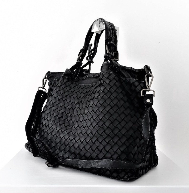 Pu&ograve; includere: Borsa tote in pelle nera intrecciata con manico superiore e tracolla rimovibile.