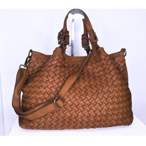 Pu&ograve; includere: Una borsa tote in pelle marrone con un design intrecciato. La borsa ha due manici superiori e una lunga tracolla.