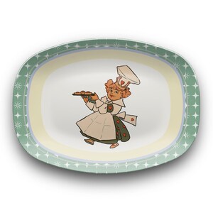 May include: Oval serving platter with a whimsical illustration of a chef holding a tray of baked goods. The platter has a light green border with starburst designs and a cream-colored interior.