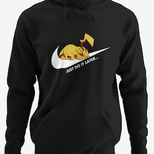 Könnte beinhalten: Schwarzer Kapuzenpullover mit weißem Nike-Swoosh und einem schlafenden Pikachu-Charakter. Der Text "JUST DO IT LATER..." ist darunter gedruckt. Der Pullover hat eine Vordertasche und eine Kapuze mit Kordelzug.