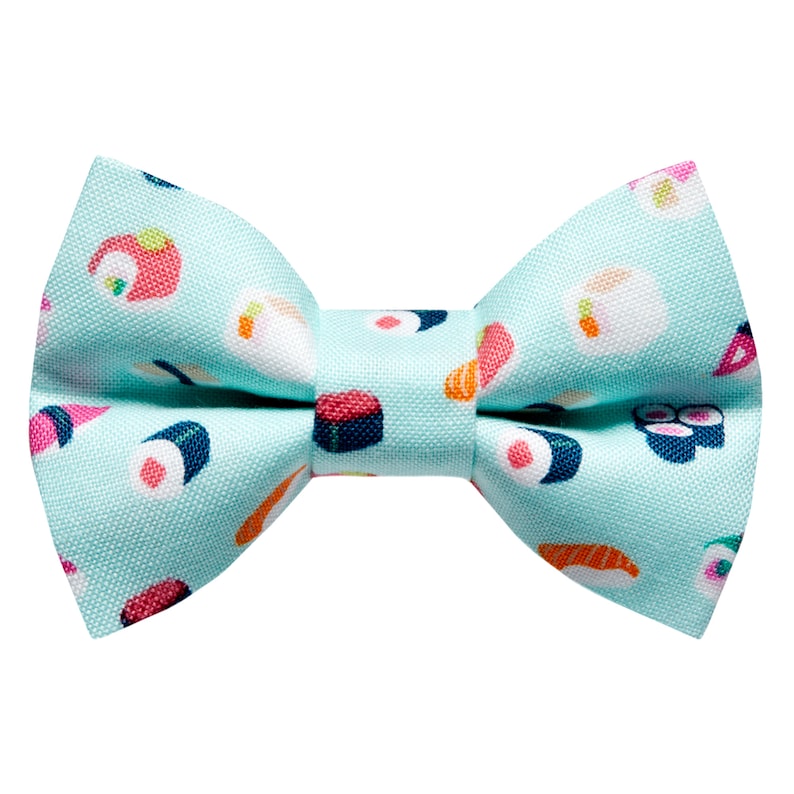May include: A light blue bow tie with a sushi pattern. The bow tie features various sushi rolls, including maki, nigiri, and sashimi.
