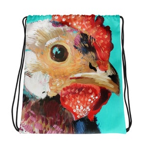 May include: A drawstring bag with a colorful painting of a chicken's head on a turquoise background. The chicken's eye is large and brown, and its comb is red with white dots.
