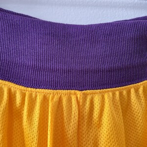 Pu&ograve; includere: Primo piano di un tessuto a rete giallo con una fascia in vita viola a coste. Il tessuto giallo ha un aspetto strutturato. La fascia in vita viola &egrave; di colore pieno. L'immagine &egrave; ben illuminata e i colori sono vibranti.