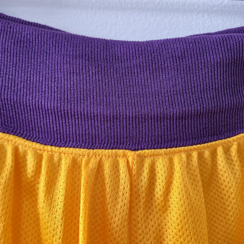 Pu&ograve; includere: Primo piano di un tessuto a rete giallo con una fascia in vita viola a coste. Il tessuto giallo ha un aspetto strutturato. La fascia in vita viola &egrave; di colore pieno. L'immagine &egrave; ben illuminata e i colori sono vibranti.