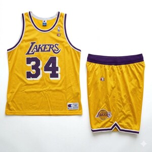 Pu&ograve; includere: Un completo da basket giallo composto da maglia e pantaloncini. La maglia presenta la scritta "Lakers" e il numero "34" in viola. I pantaloncini hanno il logo dei Lakers e un girovita viola. Il completo &egrave; prodotto da Champion.