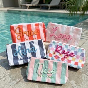Puede incluir: Cinco neceseres con varios diseños y texto. Las bolsas presentan nombres como "Grace", "Lana", "Hana", "Rose" y "Nice". Las bolsas tienen patrones de rayas y cuadros, con cierre de cremallera.