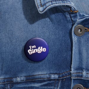 May include: A blue button with white text that reads "I'm Single" on a denim jacket.