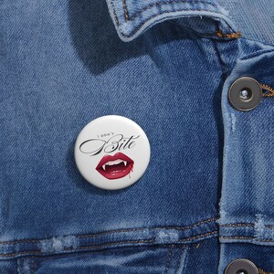 May include: A white button with a red vampire mouth and fangs with dripping blood. The text "I don't Bite" is written in black cursive above the mouth.
