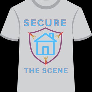 May include: A light gray t-shirt featuring a graphic print of a purple shield containing a light blue house icon. Three orange flame-like shapes point outward from the shield. The text SECURE THE SCENE is printed in light blue with a purple outline.
