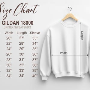 Puede incluir: Una sudadera unisex blanca Gildan 18000 colgada de una percha de madera. La imagen incluye una tabla de tallas con medidas en cm para el ancho, el largo y el largo de la manga, que van desde la talla S hasta la 5XL.