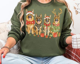 Op de afbeelding: Een olijfgroene sweatshirt met een aquarel illustratie van vier Duitse herders in kerstoutfits. Elke hond draagt een kerstmuts, sjaal of trui, met cadeaus en feestelijke versieringen.