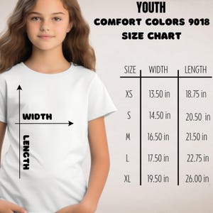 Puede incluir: Una camiseta blanca con una tabla de tallas para j&oacute;venes Comfort Colors 9018. La tabla enumera las tallas XS a XL, con medidas de ancho y largo en pulgadas. Una persona joven lleva la camiseta.