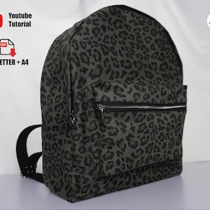 Könnte beinhalten: Ein Rucksack mit Leopardenmuster in Grün- und Schwarztönen. Er hat eine Reißverschlusstasche vorne und schwarze Träger. Das Bild enthält den Text "Youtube Tutorial" und "US_LETTER + A4".
