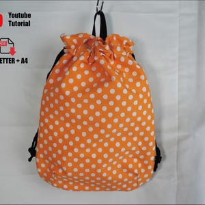 Pode incluir: Mochila laranja com cordão e bolinhas brancas. A bolsa tem cordões pretos e uma alça preta. A imagem também inclui o texto "Youtube Tutorial" e "US_LETTER + A4".