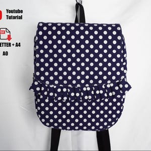 Puede incluir: Mochila azul marino con lunares blancos y solapa con volantes. La bolsa tiene correas y un asa negras. La imagen también incluye el texto "Youtube Tutorial" y "US_LETTER + A4 AO".