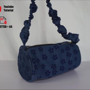 May include: A denim blue, cylindrical handbag with a floral pattern. The bag has a zipper closure and a ruched handle. The image also includes the text "Youtube Tutorial" and "US_LETTER + A4".