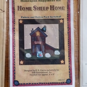 May include: Three packaged craft patterns featuring sheep-themed designs. The patterns include "Karen's Coop Country Lambs," "Home Sheep Home," and "Wooly Sheep Wall Quilt Pattern." The patterns are in plastic sleeves.