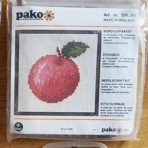 May include: Four cross-stitch needlecraft kits in plastic packaging. The kits feature images of a woman and child, two apples, and a pear. Each kit is labeled "pako HANDWERKEN" and "MADE IN HOLLAND". The kits measure 9 x 9 cm.