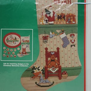 May include: A Dimensions Christmas Memories Stocking counted cross stitch kit in a plastic package. The packaging features a tan stocking with a Santa, a teddy bear in a red chair, a rocking horse, and various holiday motifs. It measures 16 inches long.