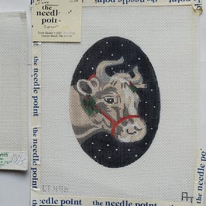 May include: Two needlepoint canvases. One features the Texas flag with a white star on a blue field and red and white stripes. The other depicts a cow's head with a red halter against a black background with white dots.